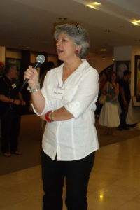 Miami art-marketing salon leader Debra Cortese talks at an exhibit opening of member art.