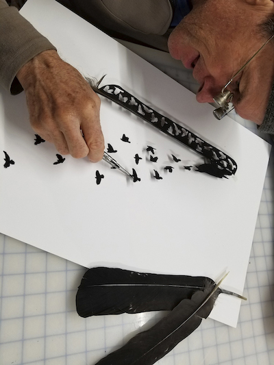 Artist Chris Maynard at work on carved feather artwork