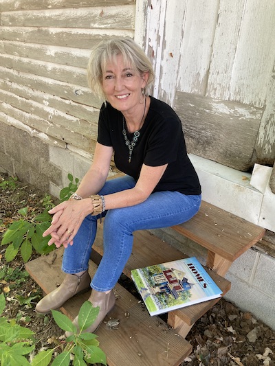 artist Leisa Collins sitting on step of house | on Art Biz Success