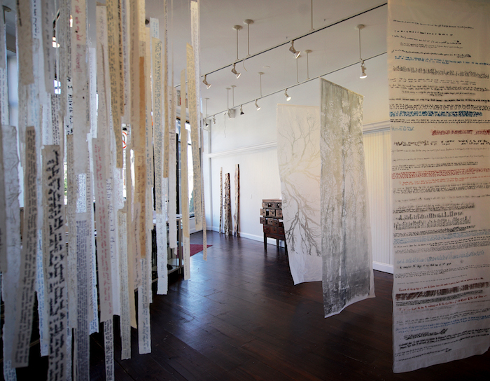 Memory project art installation artist Christine Aaron strips of printed paper hanging from ceiling | on Art Biz Success