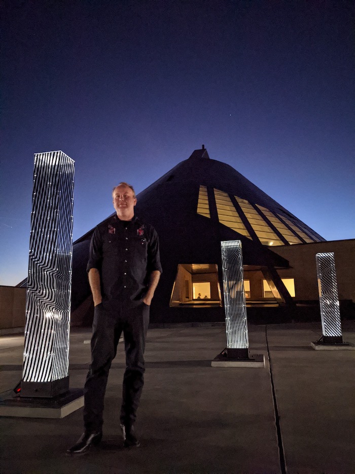 artist Collin Parson standing in front of his light sculpture at the University of Wyoming | on Art Biz Success