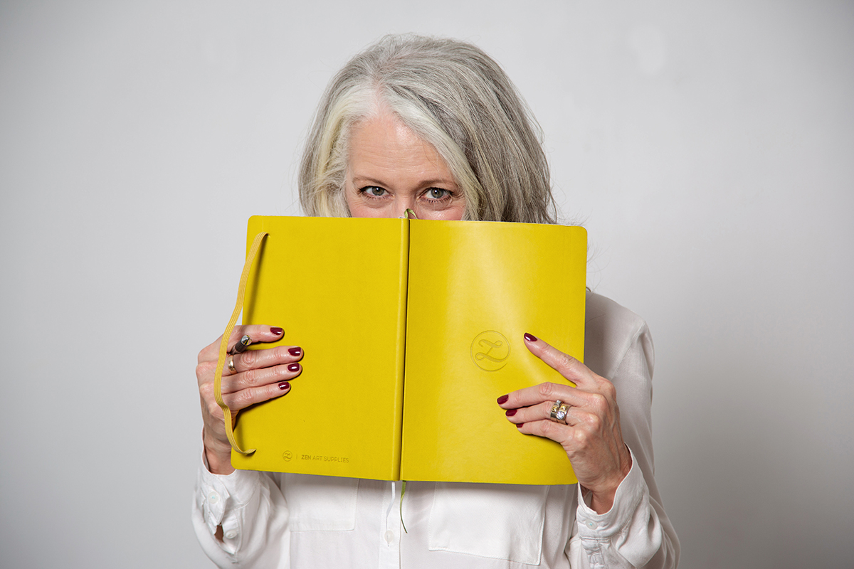 Alyson Stanfield behind yellow notebook with eyes peeping over the top