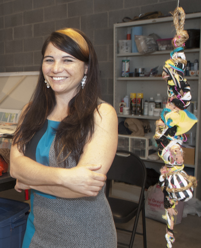 Louise Martorano stands with arms crossed in artist studio | on Art Biz Success