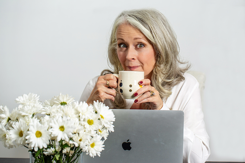 Alyson Stanfield with coffee cup, computer, and daisies