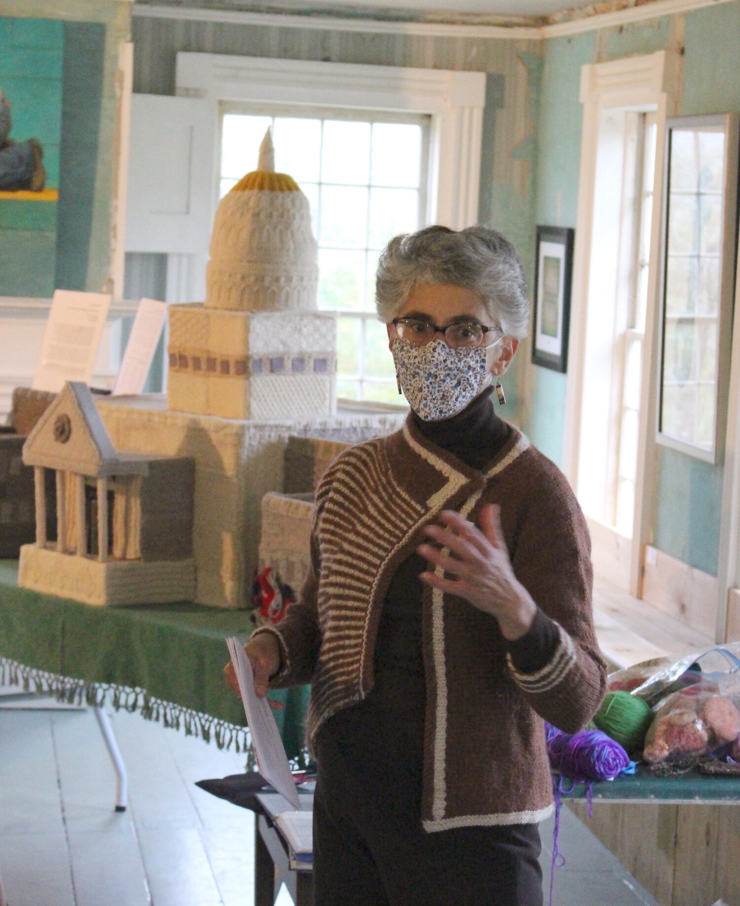 artist Eve Jacobs-Carnahan stands in front of her knit Capitol building while leading a maker circle at Kent Museum in Vermont