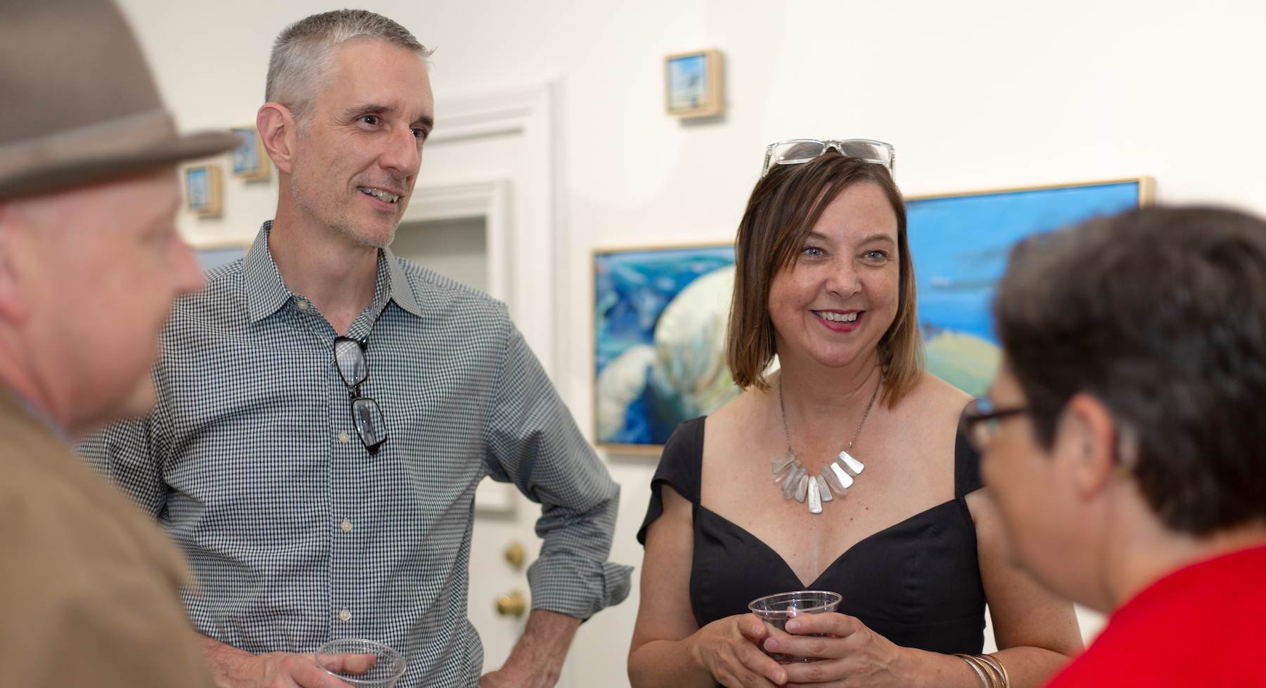 Artists John and Caroline Rufo at an exhibition opening in front of their art - talking with guests | on Alyson Stanfield