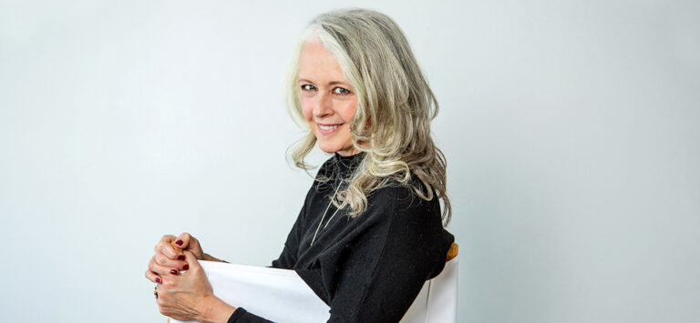 Alyson Stanfield with black shirt looking over the back of a white director's chair