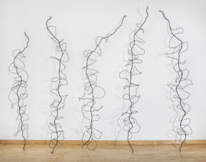 Steel wire sculptures of vine outlines on a light wood floor with white wall behind | on Art Biz success
