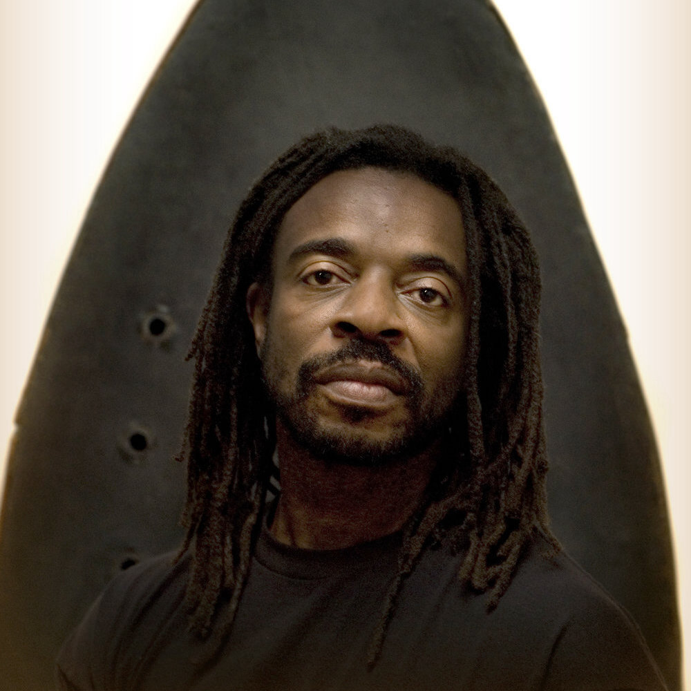 artist Willie Cole with long dreadlocked hair and black shirt
