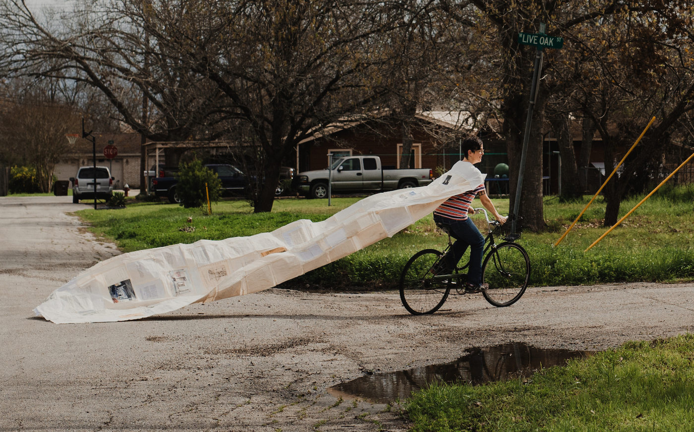 Photo of a woman riding a bike with a 12 foot cape trailing behind her | on Art Biz Success
