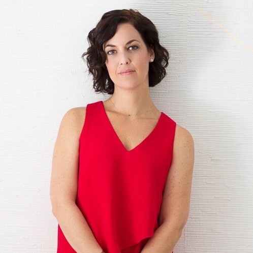White woman with shoulder length dark hair wearing a red tank top standing against a white background | on Art Biz Success