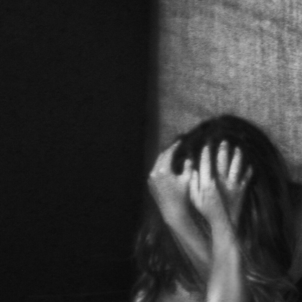Black and white photo of woman woman burying her face in her hands.