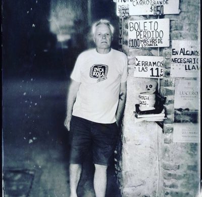 Artist Geoffrey Gorman leaning against signs. In black and white
